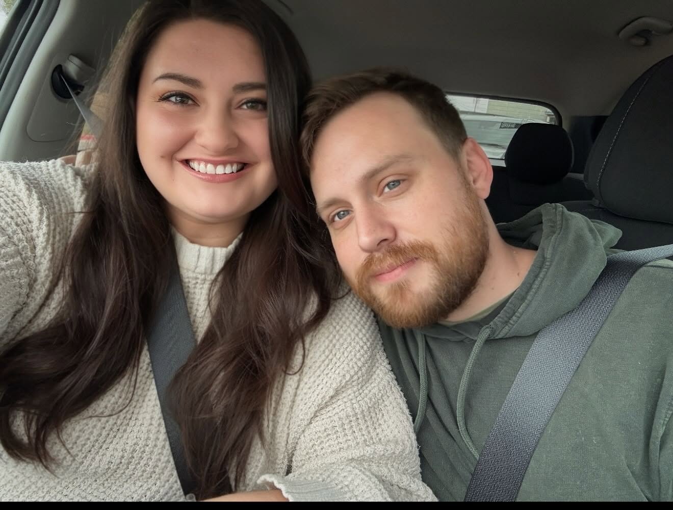 Cassie and Louis smiling together in the car